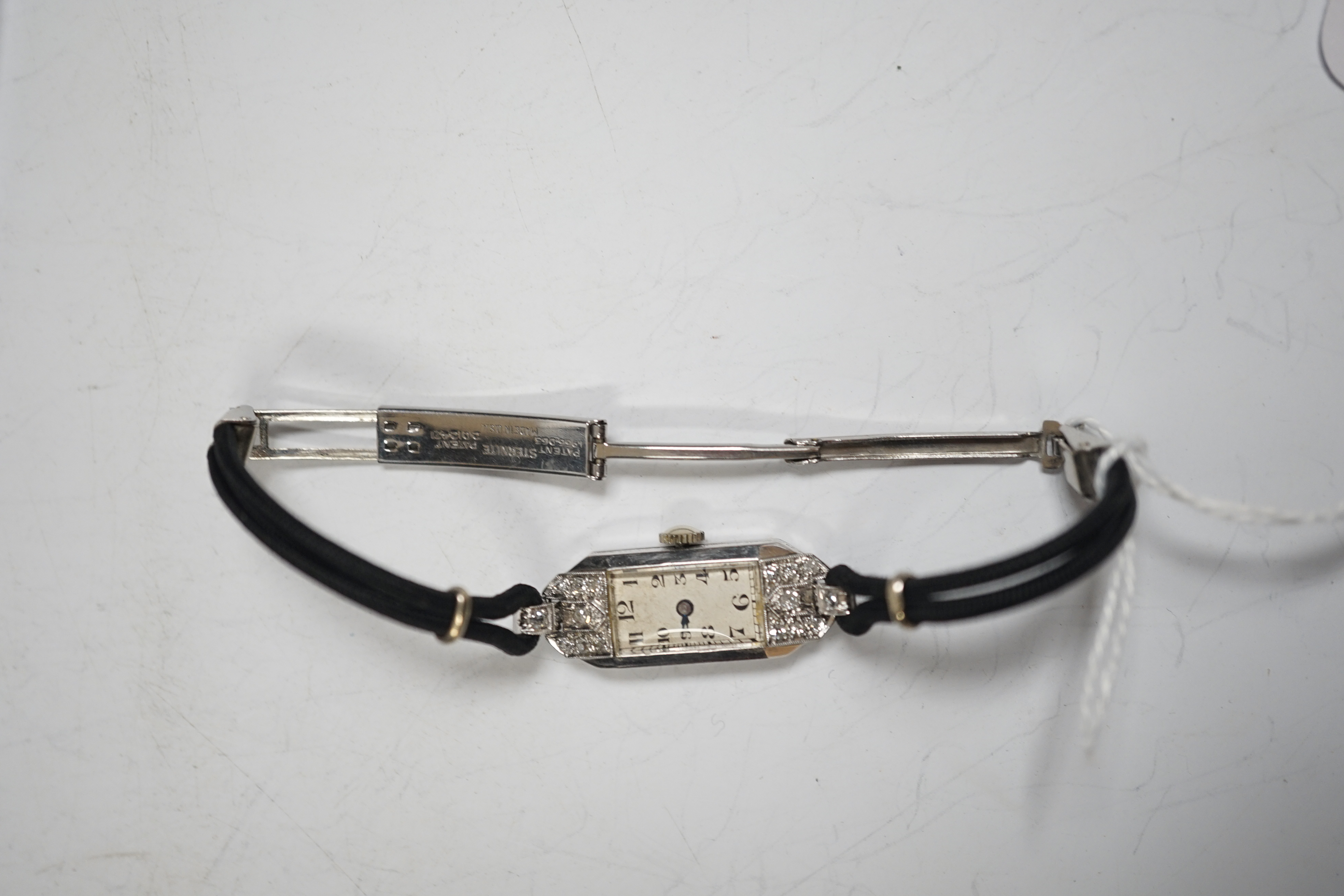 A lady's mid 20th century white metal, inscribed 'All Platinum' and diamond chip set rectangular manual wind cocktail wrist watch, on a twin fabric strap with sterling clasp, cased diameter 13mm.